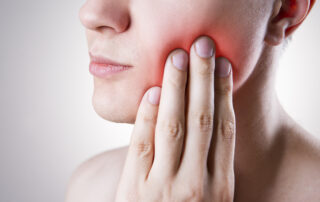 Close up of a person's hand on their jaw with glowing red pain