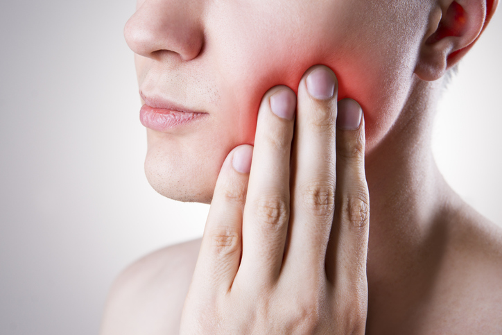 Close up of a person's hand on their jaw with glowing red pain